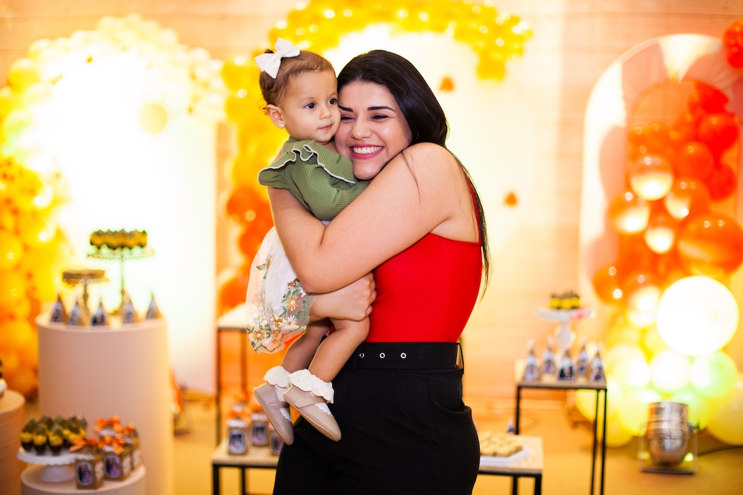 Mom hugging her child, posing for a photo at a party. There are lots of party decorations.